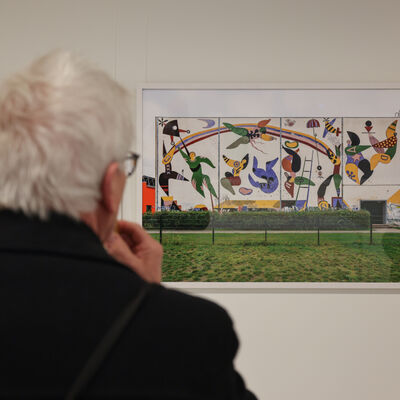 Ein Besucher der Ausstellungseröffnung betrachtet eine Fotografie von Martin Maleschka, die ein Werk von Erika Stürmer-Alex in Rüdersdorf zeigt.