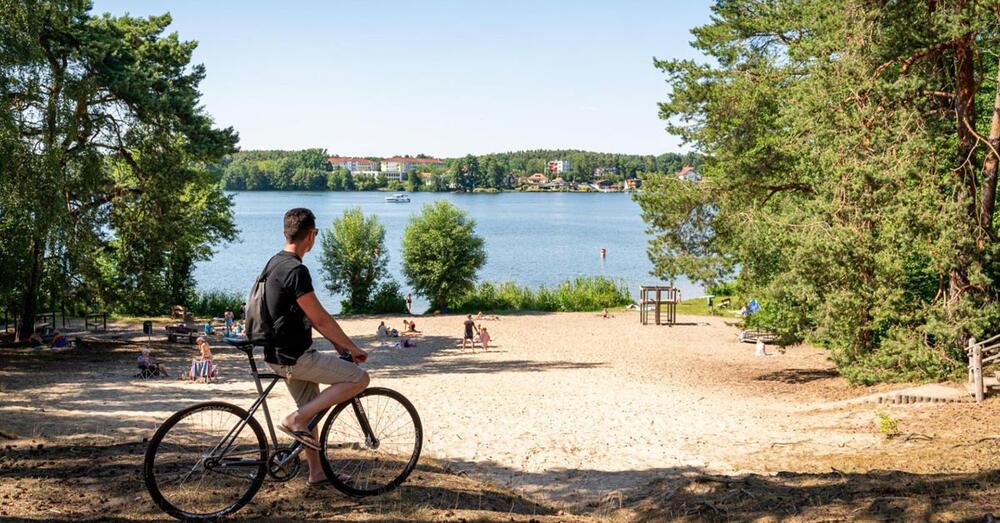 Fahrradfahrer steht am Ufer eines Sees
