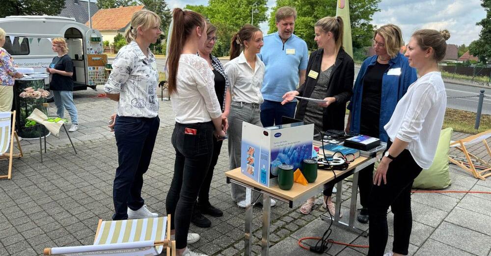 Frank Steffen steht gemeinsam mit einigen Personen am Stand der Kreisverwaltung auf dem Vorplatz des Campus in Brieskow-Finkenheerd.