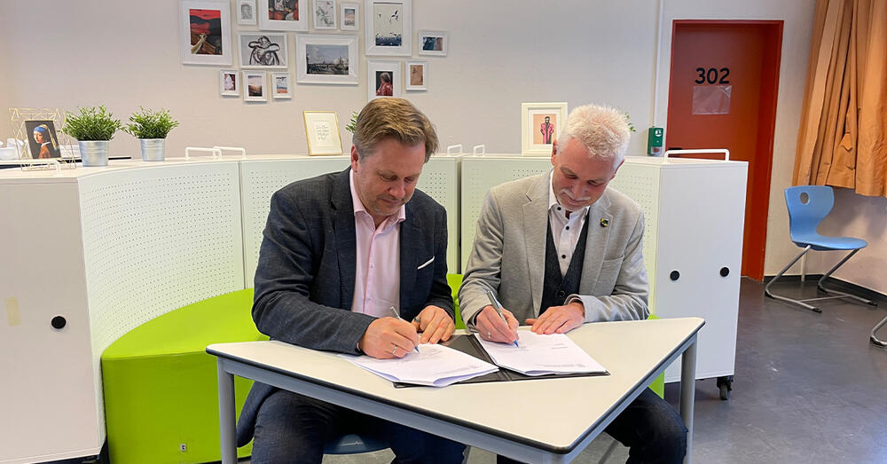 Landrat Frank Steffen und der B&uuml;rgermeister aus Erkner Henryk Pilz unterzeichnen am Tisch sitzend den "Letter of Intent".