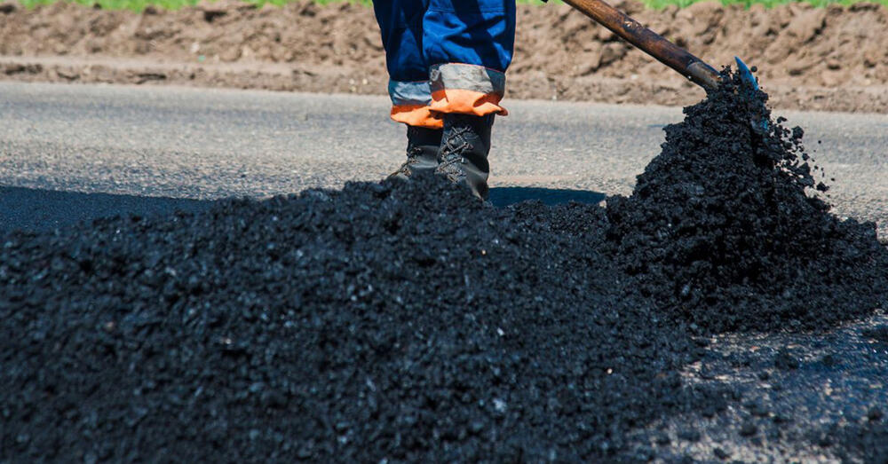Bauarbeiter beim Verteilen des Asphaltbelages.