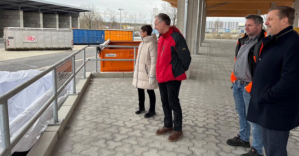 Landrat Frank Steffen steht gemeinsam mit weiteren Personen auf einer Rampe auf dem Gel&auml;nde des Kommunalen Wirtschaftsunternehmens Entsorgung.