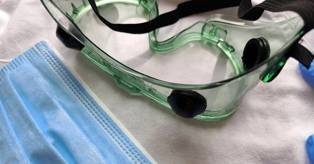 Auf einem Tisch liegen eine Atemschutzmaske eine Schutzbrille.