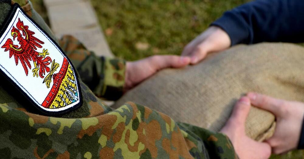 Ein Bundeswehrsoldat &uuml;bergibt einen Sandsack an einen Helfer.